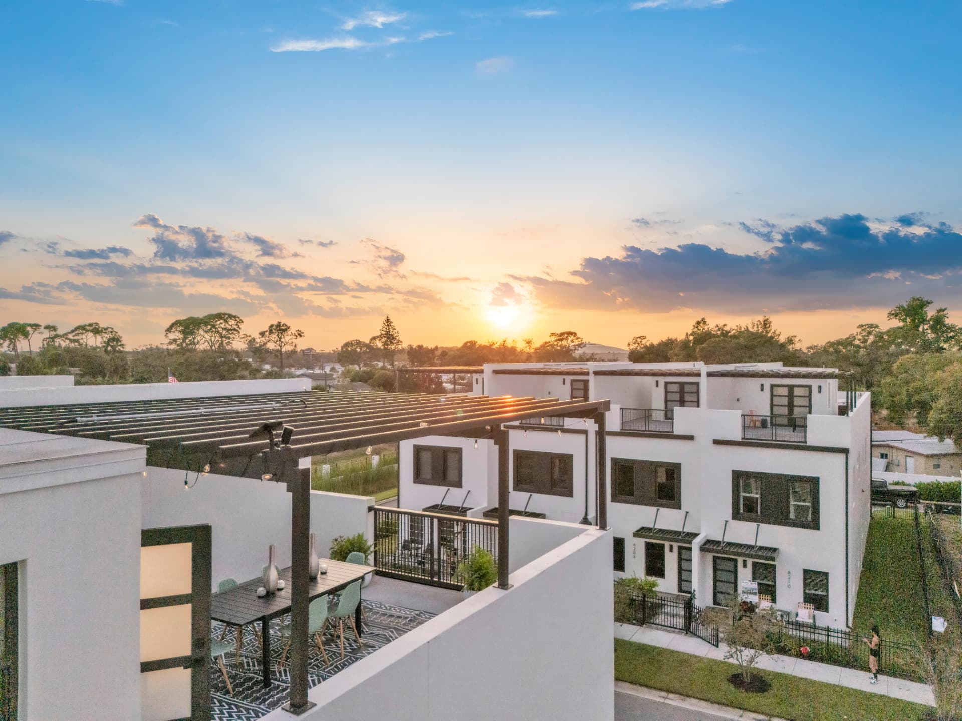 Sunset over a pergola-covered rooftop terrace and the townhome row at Latitudes in the Park, Pinellas Park, Florida