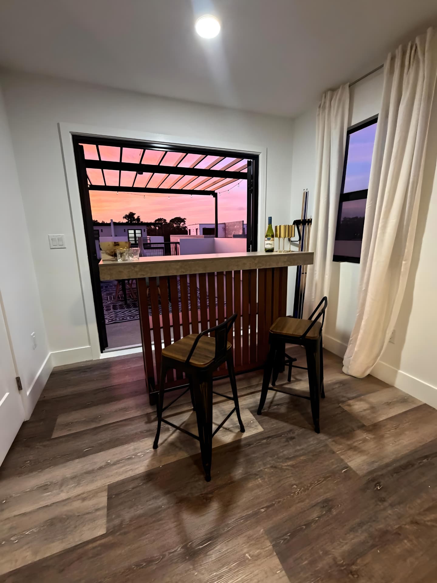 Loft bar looking out through open doors to a rooftop terrace at sunset over Pinellas Park, Florida