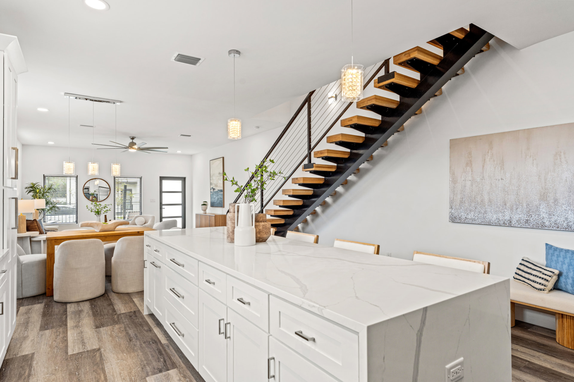 Quartz waterfall island, floating oak stair and open dining room on the main level of a Latitudes in the Park residence, Pinellas Park FL